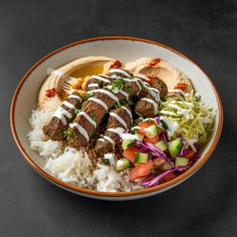 A Delico 21 Gourmet Deli bowl with rice, hummus, meat skewers, and a fresh salad.